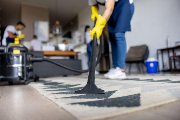 Professional cleaner vacuuming a carpet-min